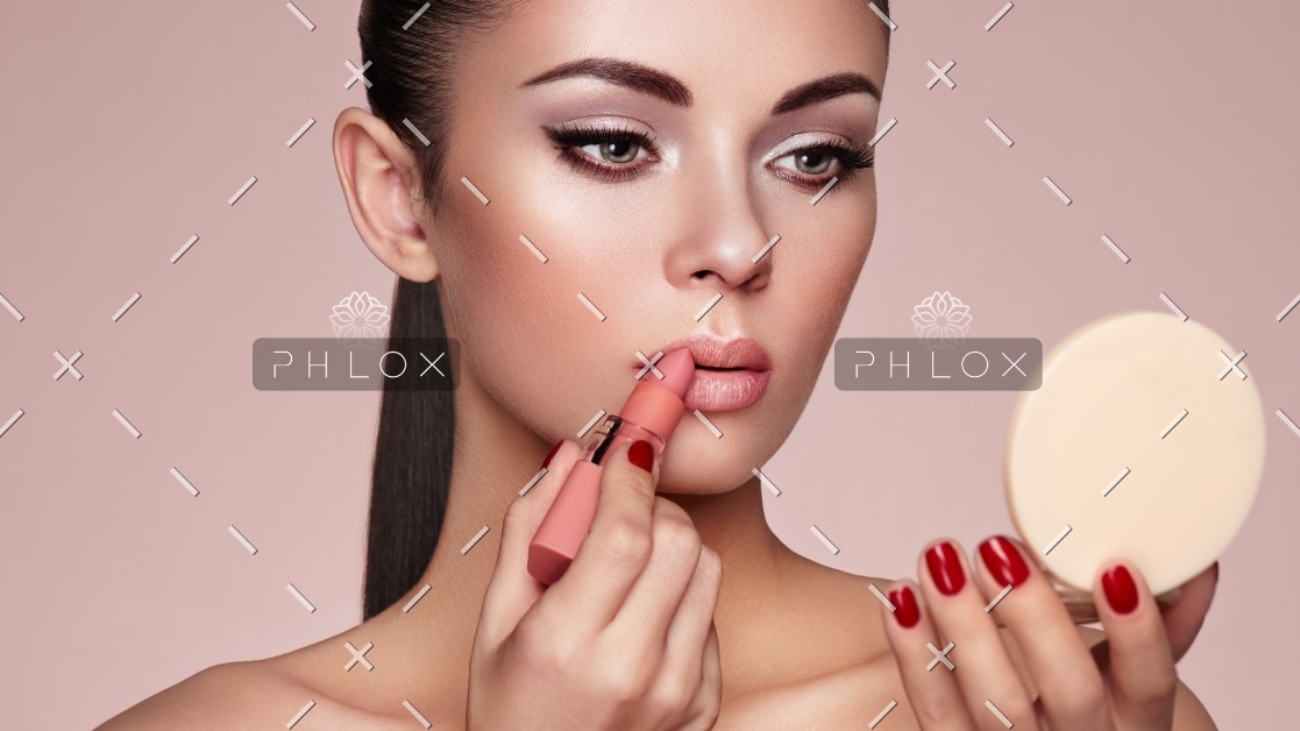 beautiful-woman-paints-lips-with-lipstick-PMB6YWP-1